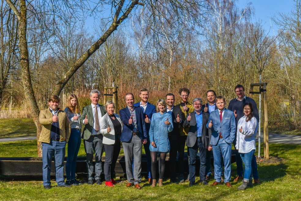 Gruppenbild der QLEE-Projektinitiatoren im Freien, bei dem alle Teilnehmer lächelnd mit erhobenem Daumen posieren.