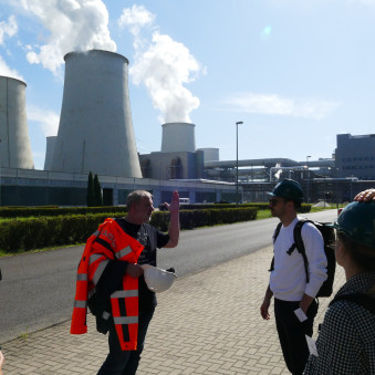 Personen vor einem Kohlekraftwerk