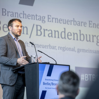 Auf der Bühne steht der Brandenburgische Wirtschaftsminister Daniel Keller und hält sein Grußwort.
