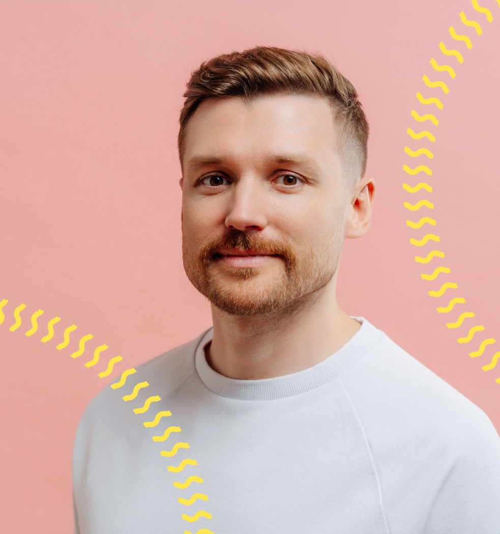 zukunftsakademie-slideshow-karsten Porträt eines Mannes in weißem Pullover vor rosa Hintergrund mit gelben Wellenlinien